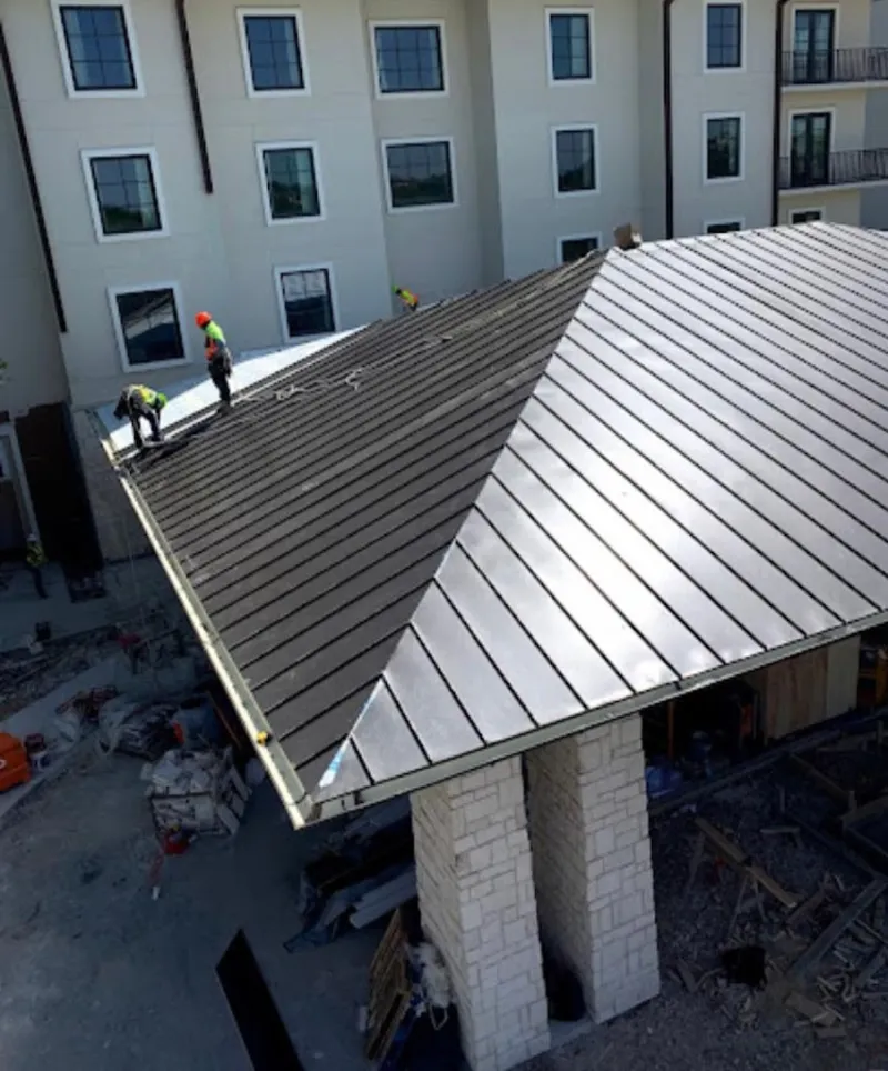 Crew installing standing seam metal roof panels on a commercial project in Dunmore